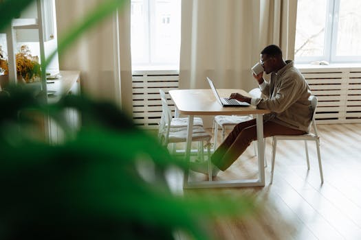 A freelancer happily working on their laptop while sipping coffee